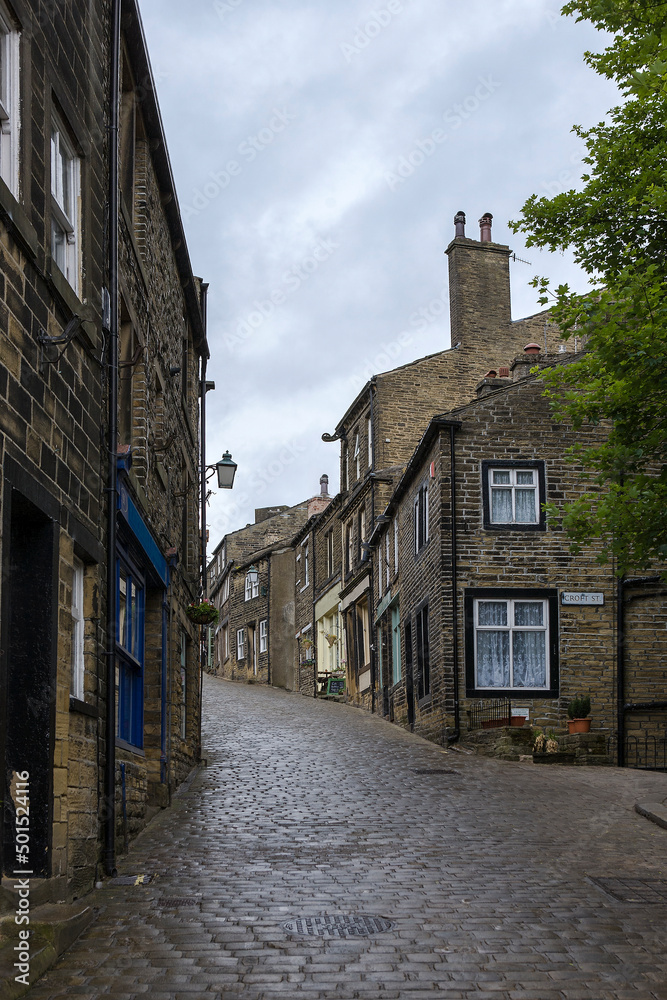 The steep and cobbled Main Street in the village of Haworth, West Yorkshire, UK: empty of people on a wet afternoon