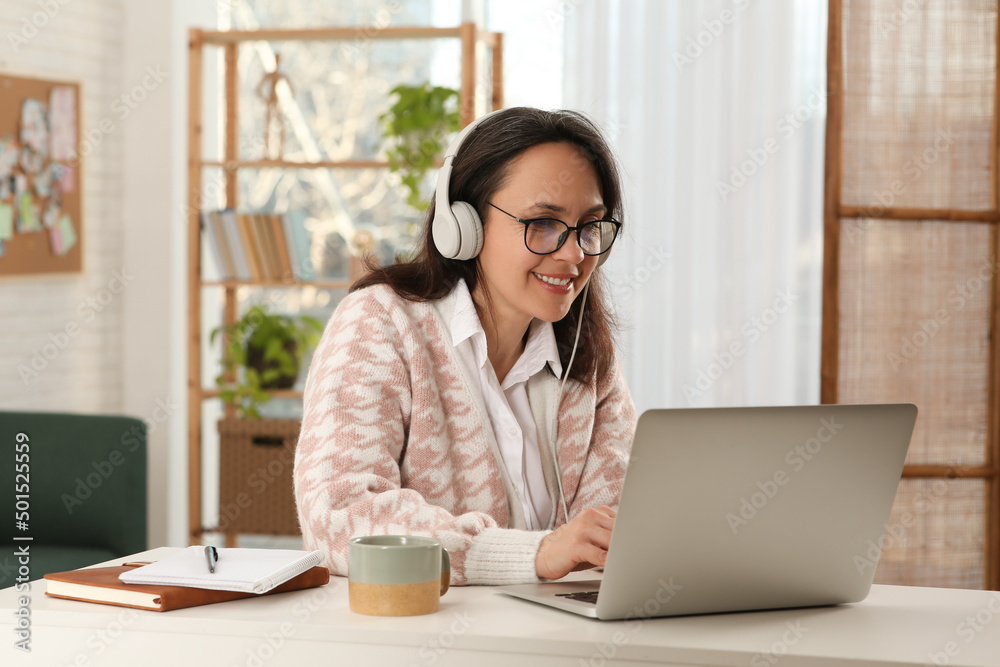 Woman with modern laptop and headphones learning at home