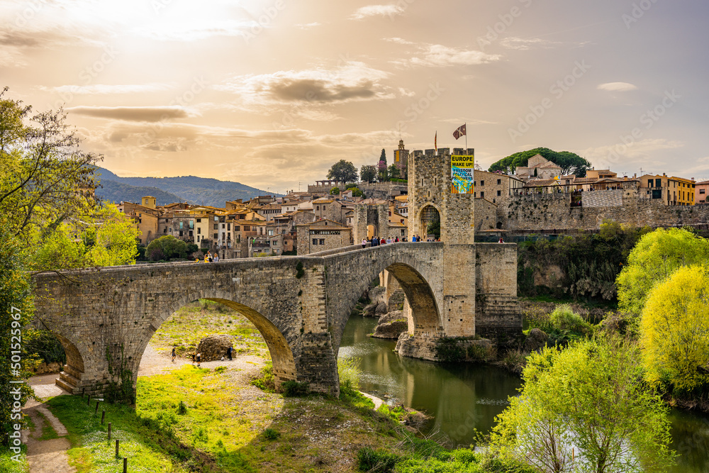 Besalu, Spain - April 14 2022 - Tourists entering via the bridge over the river Fluvia in the medieval village de Besalú, Girona, Catalonia, Spain