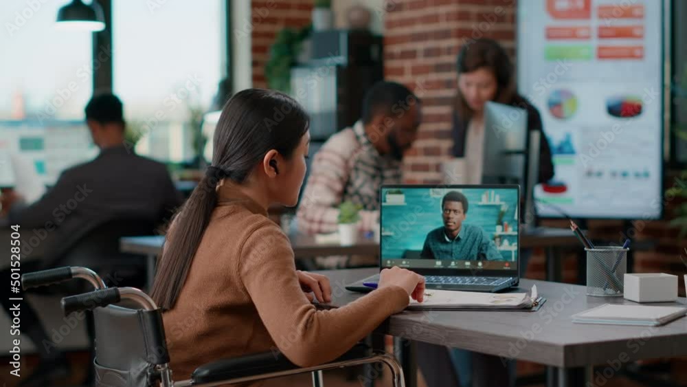 Office worker in wheelchair talking on remote videocall, using online teleconference meeting on webcam. Businesswoman having remote conversation on videoconference with colleague. Office worker in wheelchair talking on remote videocall, using online teleconference meeting on webcam. Businesswoman having remote conversation on videoconference with colleague.