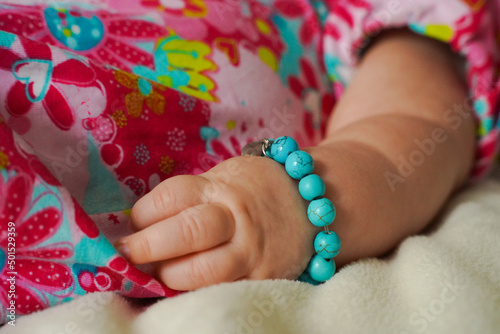 main de bébé et bracelet turquoise photo