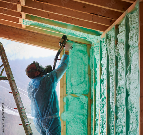 Fotografi Male builder insulating wooden frame house