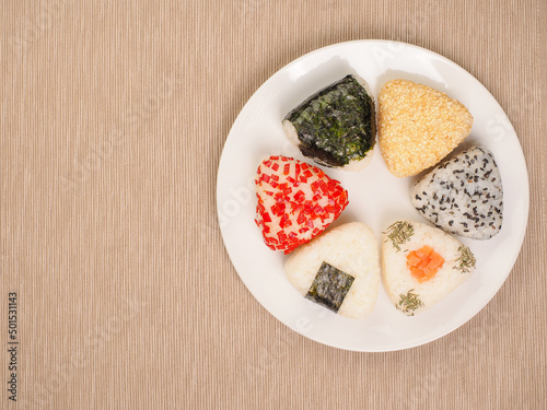 A series of shots of onigiri of various shapes and fillings on a plate. Top view. Japanese rice ball.