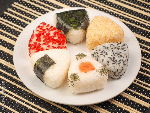 A series of shots of onigiri of various shapes and fillings on a plate. Top view. Japanese rice ball.