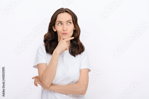 portrait of brunette caucasian woman with thoughtful face, looking away in white T-shirt on white background