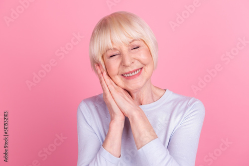 Photo of cheerful senior lady arms touch cheek sleep dream rest bedtime isolated over pink color background