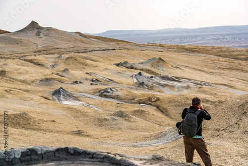 Photographer traveler shoots a landscape with mud volcanoes
