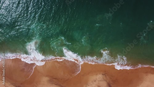 The waves roll on the shore. Yellow sandy beach with blue sea. Aerial top view