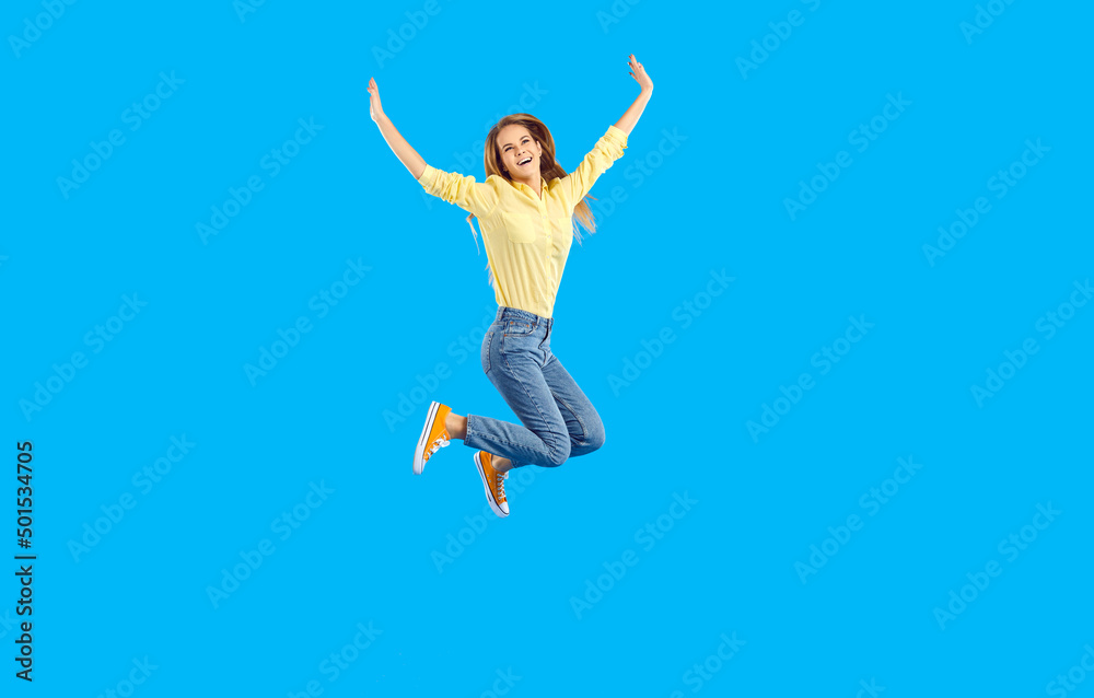 Excited millennial girl isolated on blue studio background jump high raise hands celebrate success. Overjoyed young woman feel euphoric triumph with win or victory. Energetic active teenager move. Excited millennial girl isolated on blue studio background jump high raise hands celebrate success. Overjoyed young woman feel euphoric triumph with win or victory. Energetic active teenager move.