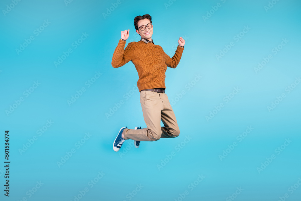 Full body photo of young guy jump up rejoice victory lucky fists hands isolated over blue color background