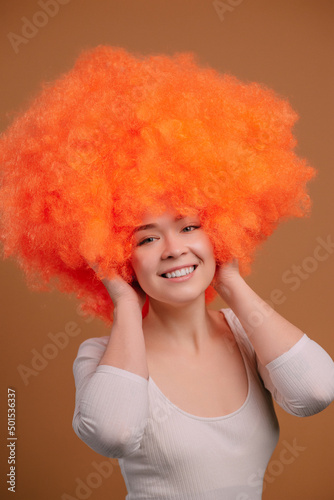 Smiling young orange haired woman on beige background. Close up portrait.