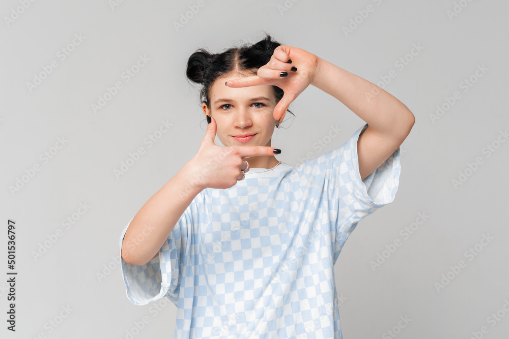 Portrait of beautiful dark-haired teen girl making frame with hands and fingers with happy face, standing in trendy t shirt over light grey background. Creativity and photography concept Portrait of beautiful dark-haired teen girl making frame with hands and fingers with happy face, standing in trendy t shirt over light grey background. Creativity and photography concept