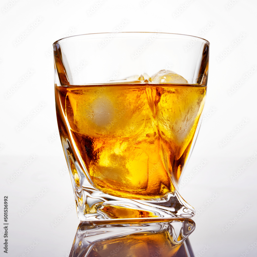 Glass of scotch whiskey with ice on a white background, close-up