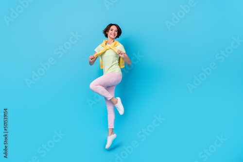 Fototapeta Naklejka Na Ścianę i Meble -  Full size photo of pretty young brunette lady jump wear t-shirt pants shoes isolated on blue background