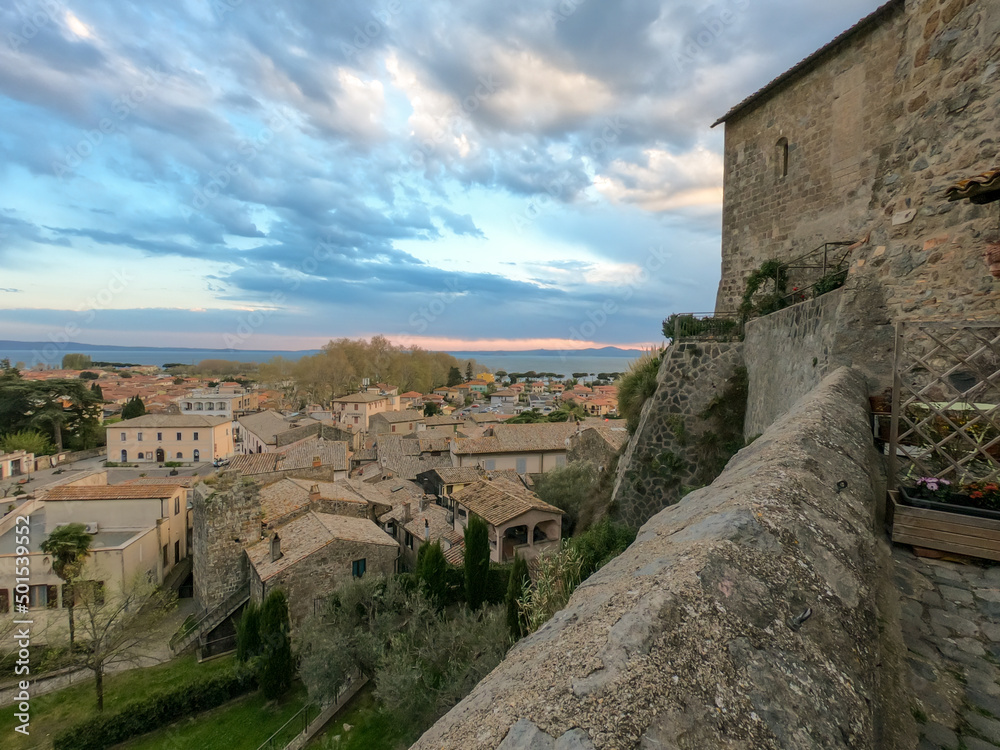 Panoramic view of the old famous city of Bolsena and Lake Bolsena at sunset. Province of Viterbo, Italy, Lazio. Cityscape and tiled roofs