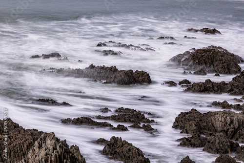 A rocky North Devon coastline, lapped by waves.  A long exposure brings motion and atmosphere. photo