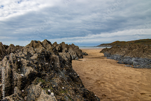 Low tide reveals this rocky beach with channels of sand leading to the sea.  The sky is a little stormy, on a chilly April day.  Mortehoe, near Woolacombe, North Devon. photo