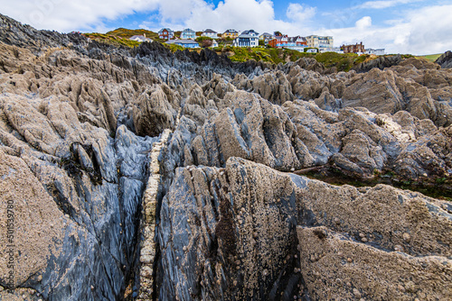 Looking up from the beach, over the rocks towards the colourful houses of Mortehoe, near Woolacombe in North Devon.  A seam of quartz seems to lead up to the village.  photo