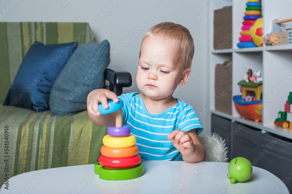 Handsome toddler boy playing with educational wooden and plastic toys in children's room.. Handsome toddler boy playing with educational wooden and plastic toys in children's room..