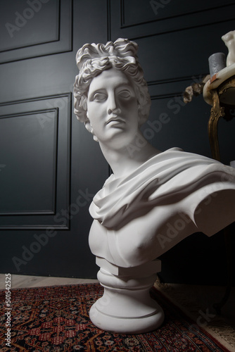 God Apollo bust sculpture. Ancient Greek god of Sun and Poetry Plaster copy of a marble statue isolated on black.