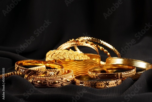 Lots of golden bracelets over a black background