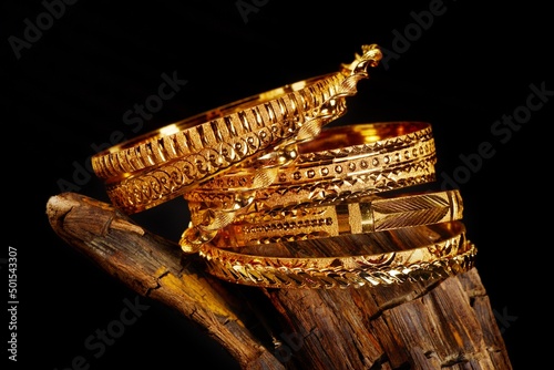 Golden bracelets over a black background, close up
