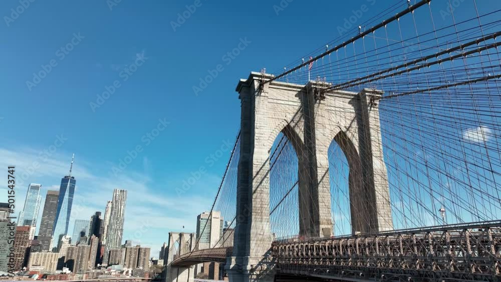 rising aerial Brooklyn Bridge from low upward view American flag Manhattan skyline New York City rising aerial Brooklyn Bridge from low upward view American flag Manhattan skyline New York City