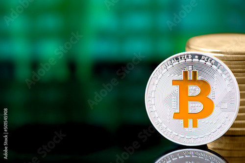 Cryptocurrency silver Bitcoin with golden symbol coin and a stack of coins on a green digital background. Currency exchange for e-commerce, saving money, transfers concept. Financial background.