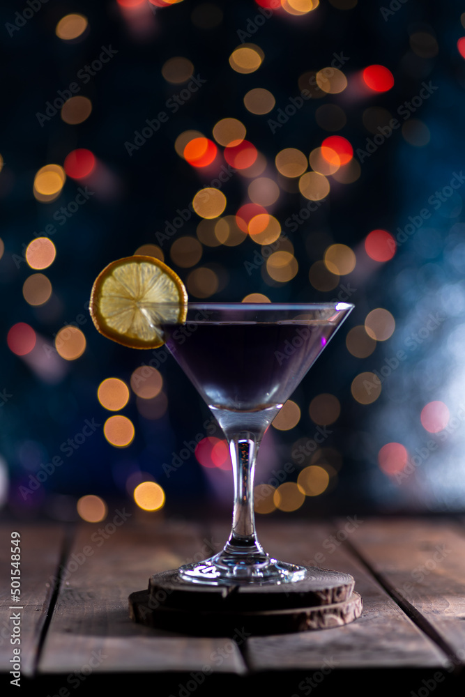 Cocktail in a triangular glass on a background of lights. A glass on the bar