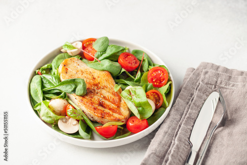 Fresh salad - spinach leaves, tomato, mushrooms, chards leaves and chicken fillet grill in a plate on the table. Top view. Healthy diet food.
