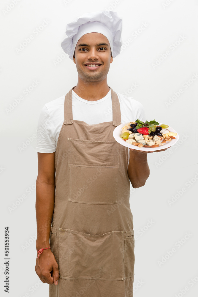 Male chef with cheese plate with grapes, nuts and strawberry Male chef with cheese plate with grapes, nuts and strawberry