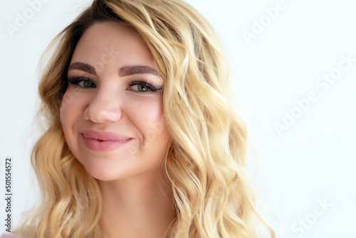 Close up portrait of beauty smiling woman with long blond hair on free white copy space, looks away. Attractive adult girl has a healthy skin.