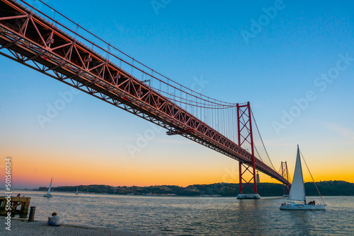 Lisbon  Portugal - november 14 2022 - Bridge of april 25th  Ponte 25 de Abril  crossing the Duoro river with in front a sailing boat