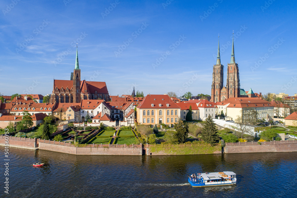 Poland. Wroclaw. Ostrow Tumski, Gothic cathedral of St. John the Baptist,  Collegiate Church of the Holy Cross, tourist ship, boat and Odra (Oder) River. Aerial view at sunset