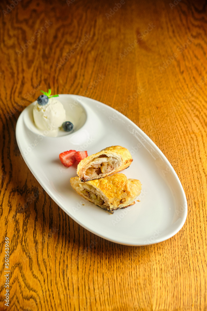 A piece of apple strudel with vanilla ice cream and strawberries A piece of apple strudel with vanilla ice cream and strawberries