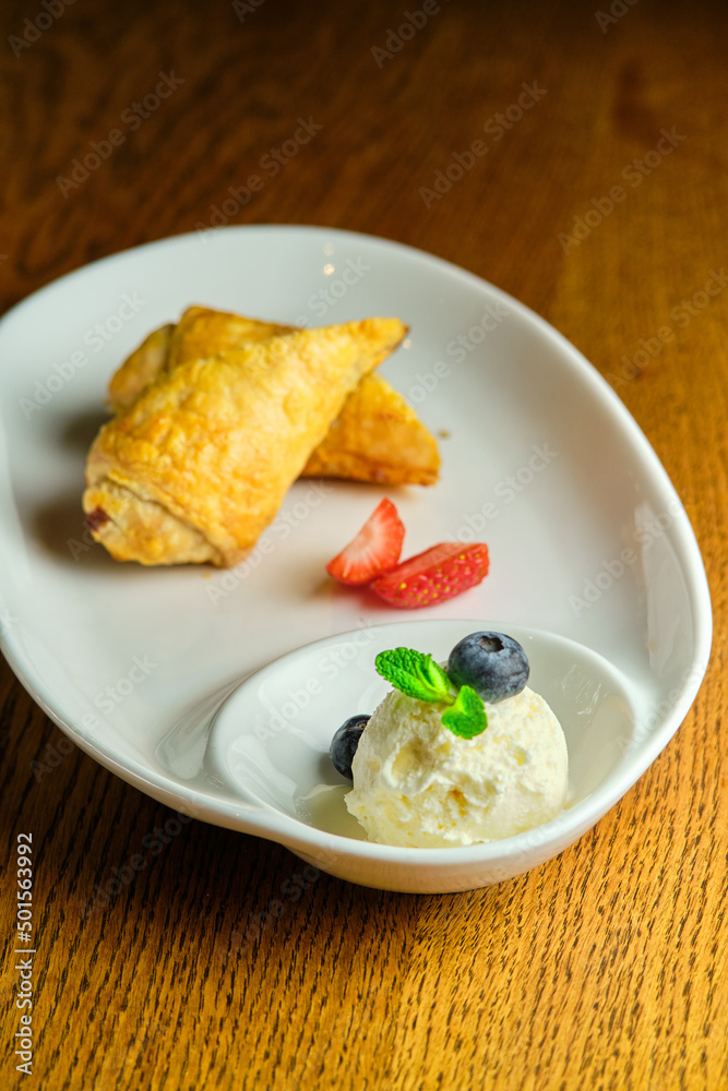 A piece of apple strudel with vanilla ice cream and strawberries A piece of apple strudel with vanilla ice cream and strawberries