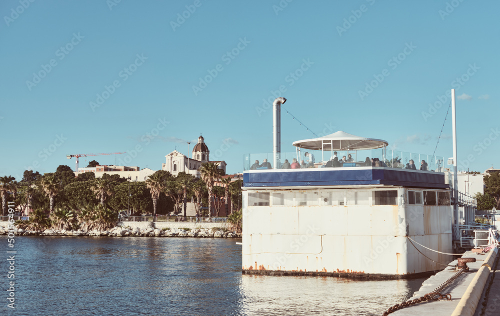 Panoramic floating bar in the commercial port of Cagliari and view of the church of Bonaria - Sardinia.