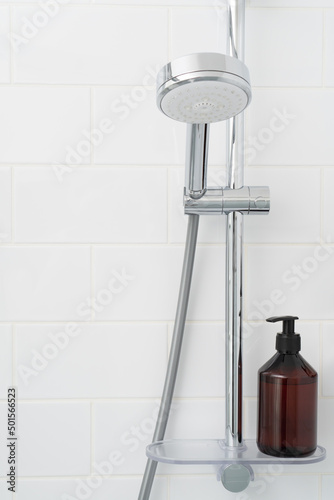 Shower rack with hanging shower head and shelf with bottle of gel.