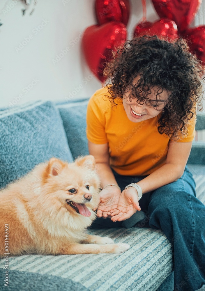 Curly haired woman playing with her dog at home. Curly haired woman playing with her dog at home.