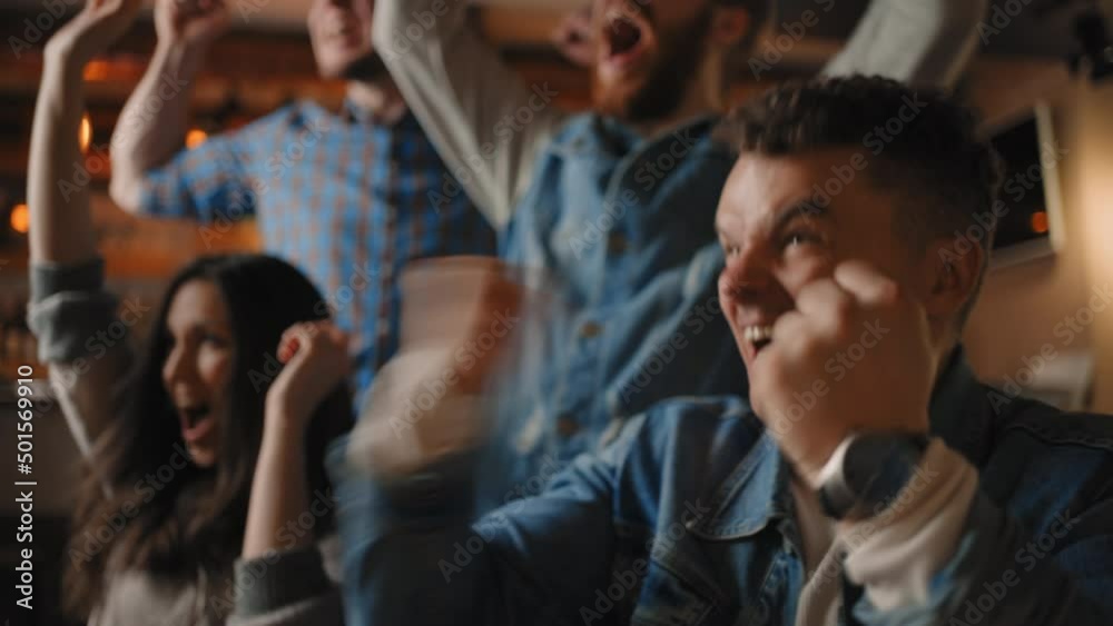 Young couple watching a sport event, jumping with hands raised, giving each other high five in sport bar. Excited crowd of sports fans applauding and celebrating their team's victory.