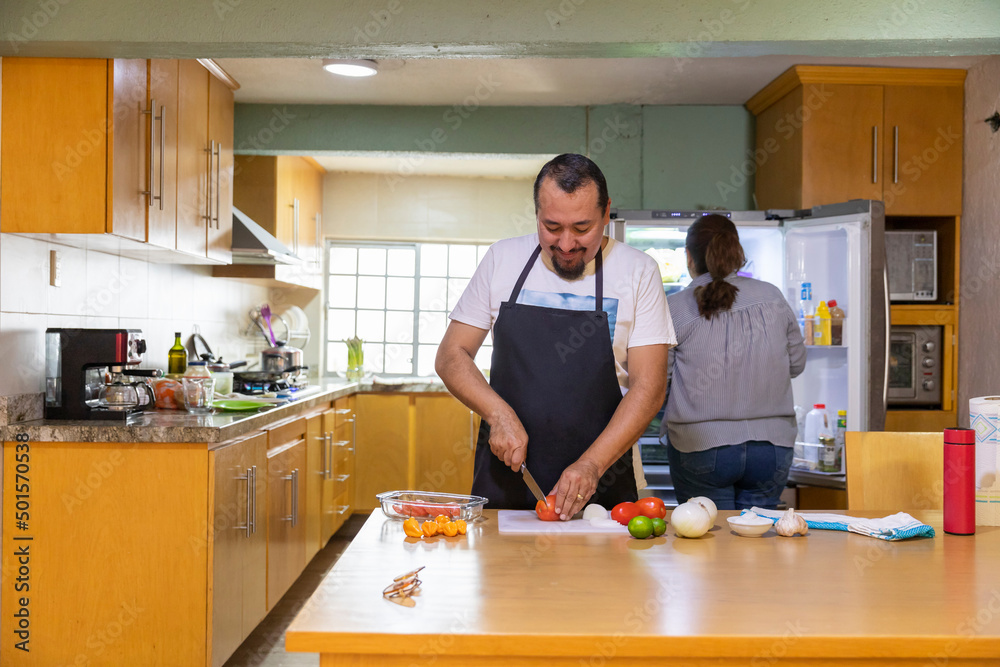 Couple cooking in yellow wooden kitchen. Couple cooking in yellow wooden kitchen.