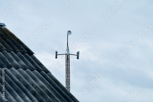 Because of the old slate roof, you can see a modern tower with antennas, the antennas broadcast a Wi-Fi Internet signal, the sky is cloudy