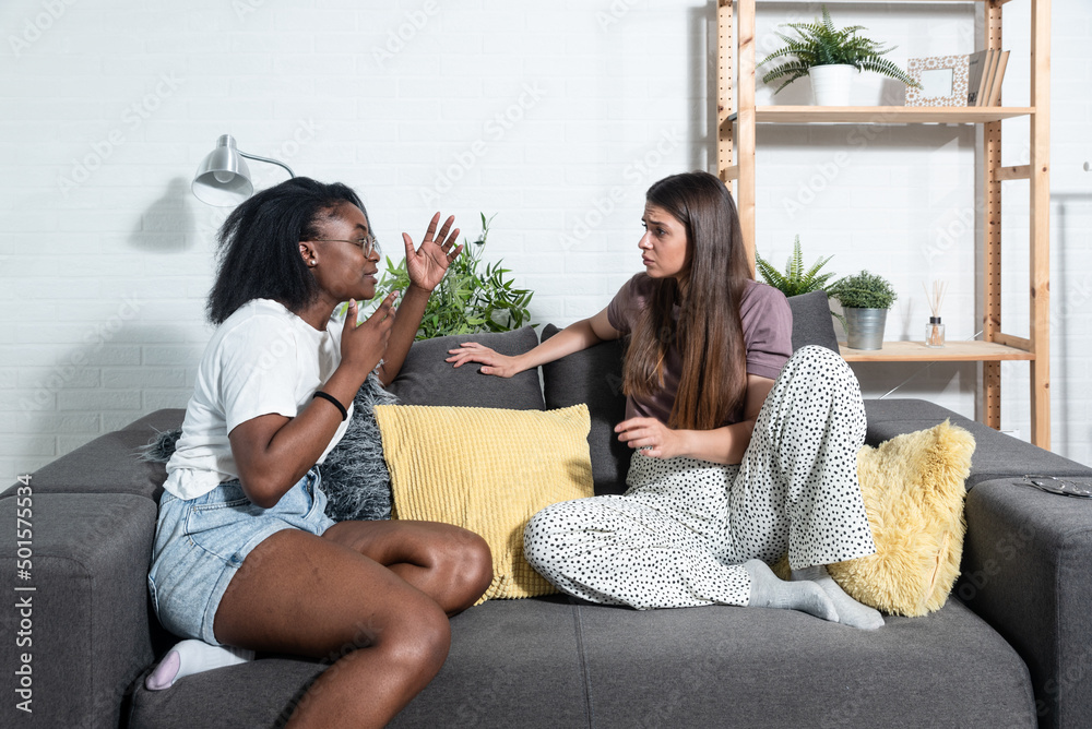 Obraz premium Young African American woman telling her bad experience and crying after she was a crime victim of robbery attack on the street. Exchange student sitting at home talking about racism experience