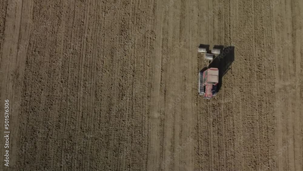 Aerial view of red crawler tractor pulling a rolling system for land plowing and seeding preparation in remote Italian countryside, top down shot Aerial view of red crawler tractor pulling a rolling system for land plowing and seeding preparation in remote Italian countryside, top down shot