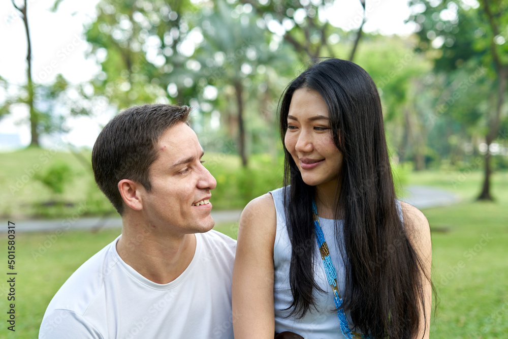 Close up portrait of a multiethnic couple smiling together in a park Close up portrait of a multiethnic couple smiling together in a park