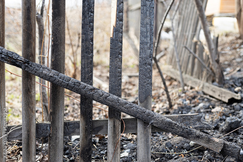 Burnt wooden fence after a fire in a rural house. Close-up of charred planks. The concept of unintentional arson. Consequences of careless handling of fire during a fire hazard