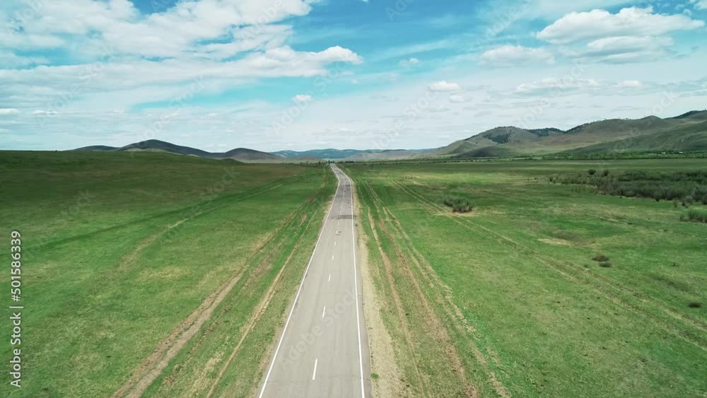 Aerial view of an asphalt road through the rural countryside area, road between green meadows. Aerial view of an asphalt road through the rural countryside area, road between green meadows.