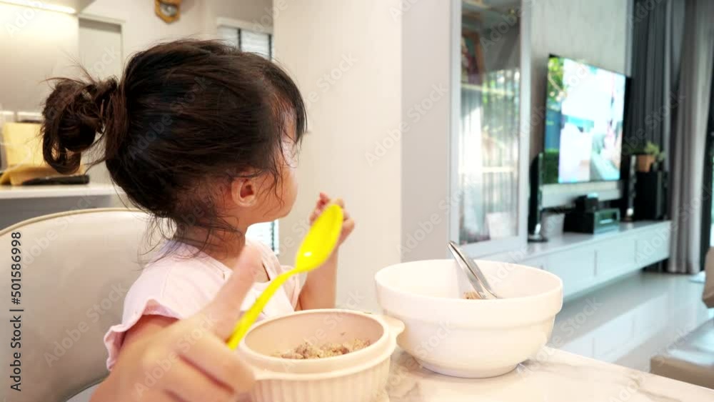 Child girl eating while watching TV at home.Not good behavior for child because child will not focus eating well. Child girl eating while watching TV at home.Not good behavior for child because child will not focus eating well.