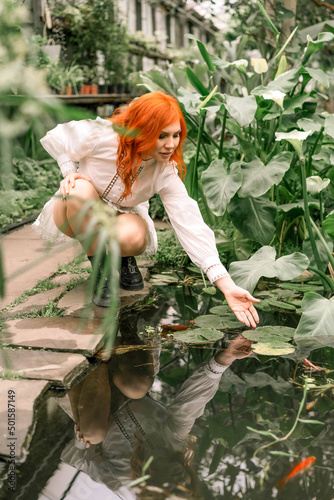 Red-haired girl walking in a tropical garden
