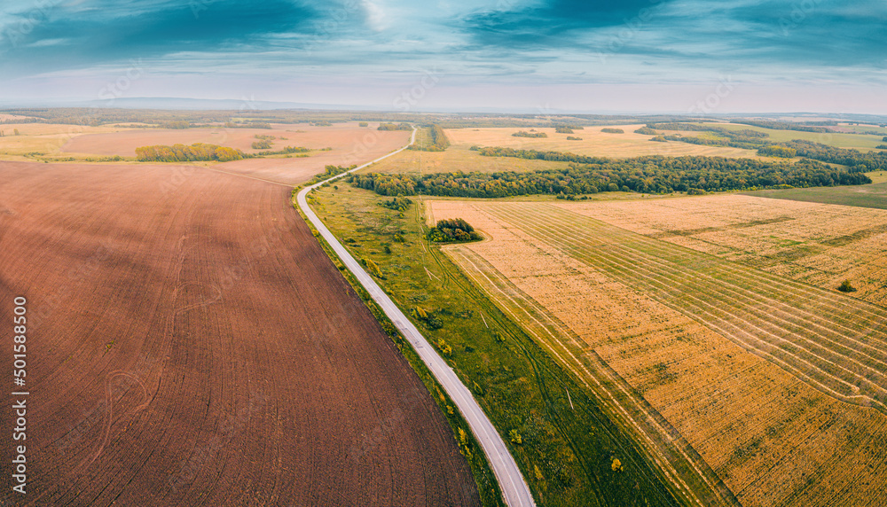 Aerial view of a plowed field and scenic road leading into the distance. Agriculture background